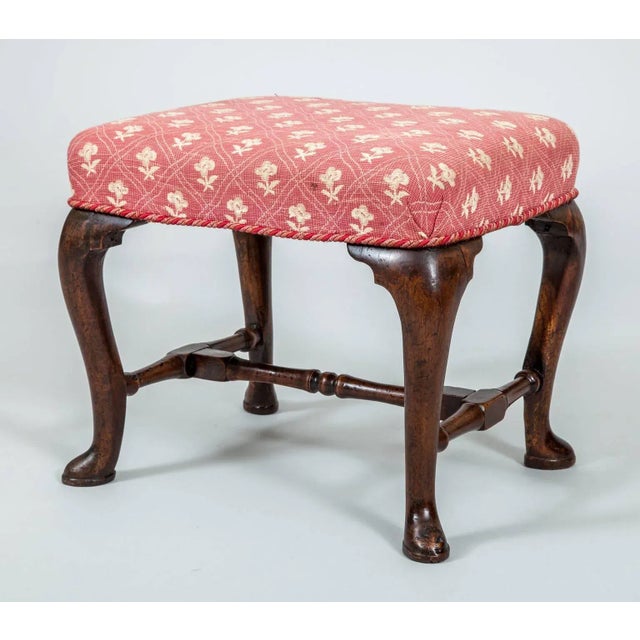 Antique Queen Anne walnut stool with cabriole legs joined by carved and turned H-shaped stretchers raised on pad feet.