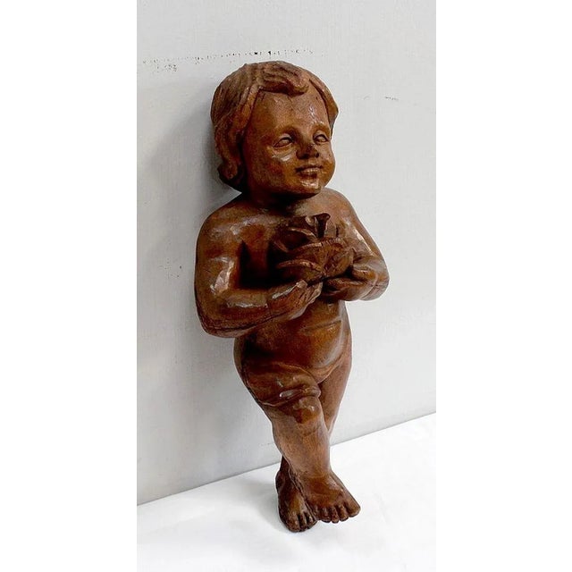 Cute Cherub Wooden Carved holding a pink and wearing a drape. His chubby face sketch a smile and laughing eyes reveals...
