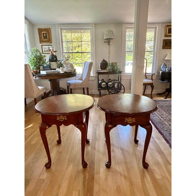 These Queen Anne side tables by Henkel Harris were made in the 1990’s of black cherry wood. The oval top sits on cabriole...