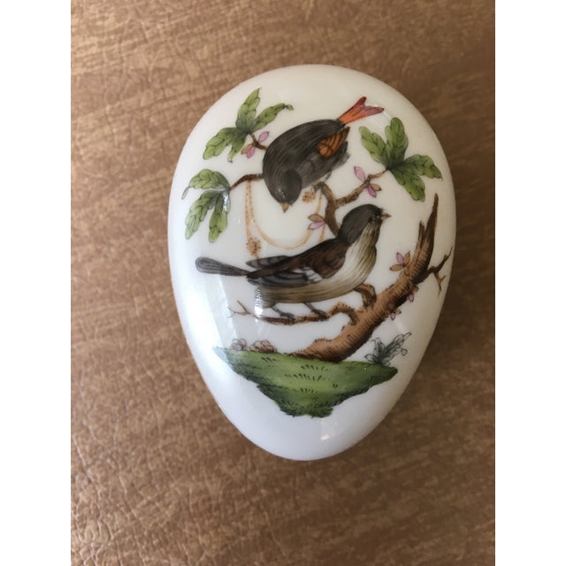 This Herend porcelain egg is part of the handpainted Rothschild Bird collection (RO). The top of the egg features two...