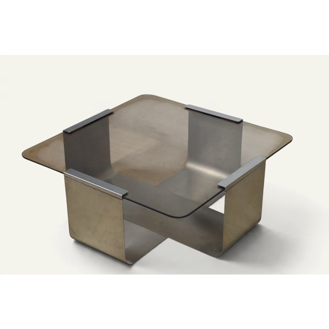 A 1970s coffee table inspired by François Monnet, combining a sculptural brushed steel base with a smoked glass top...