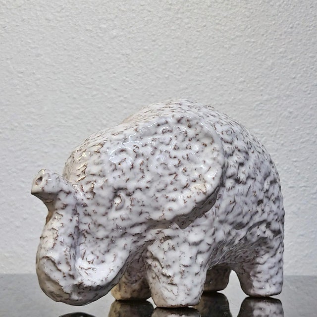 A stout figurine of a white elephant with a glossy translucent glaze revealing the red clay body underneath. Designed by...
