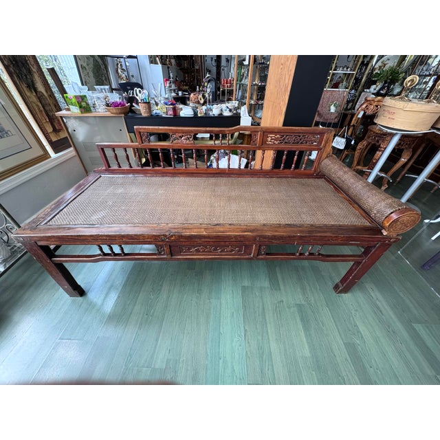 An antique Chinese provincial daybed from the late Qing dynasty, about 1880–1920, in elm with its original red-brown...