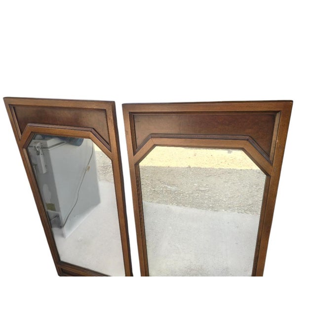 This handsome pair of vintage Mid-Century Modern wall mirrors features warm walnut-toned frames with a distinctive...