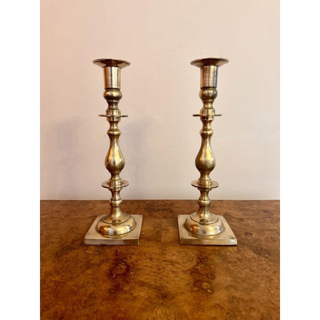 Large quality pair of brass antique candlesticks, having a quality pair of large brass candlesticks with turned shaped...