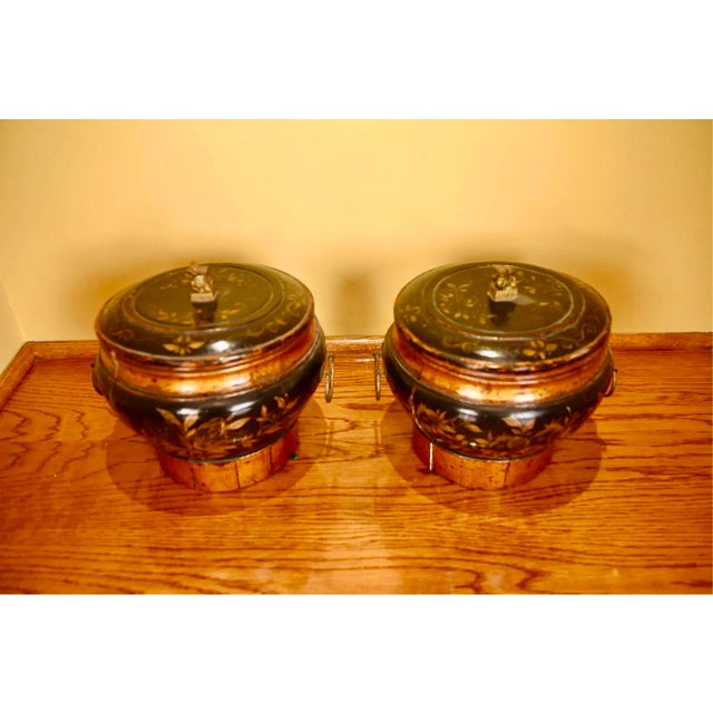 A pair of antique Chinese lacquered wooden lidded storage vessels with rounded black lacquer bodies, slightly domed lids...