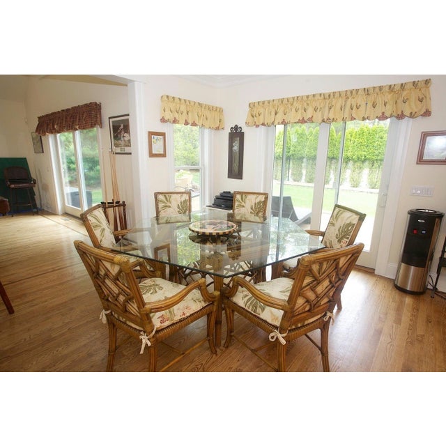 A large hexagonal McGuire style glass top dining table with a large geometric bamboo base with six legs connected by a...