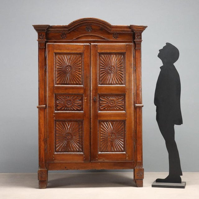 Double-piece walnut wardrobe. Tripartite doors with carved panels and ribbed moldings, a cymatium with carved rosettes...