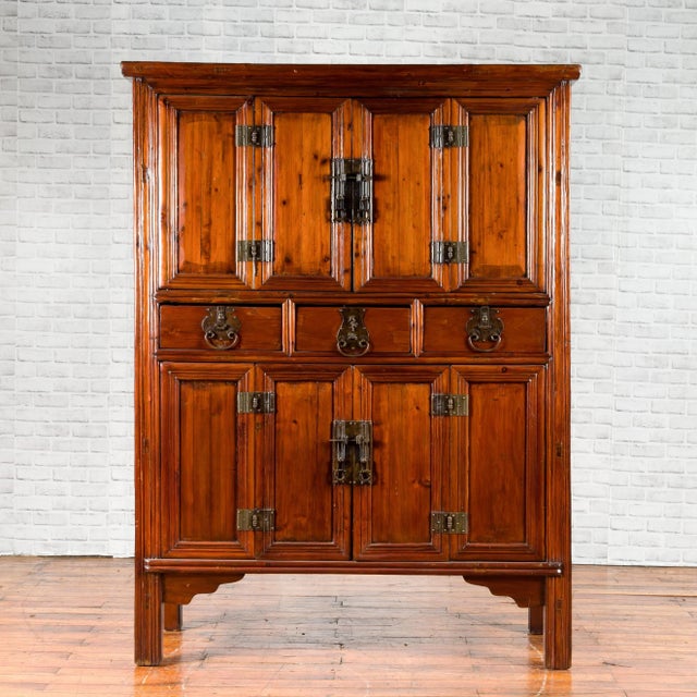 A Chinese Qing Dynasty period four accordion door cabinet from the 19th century, with three drawers and brass hardware....