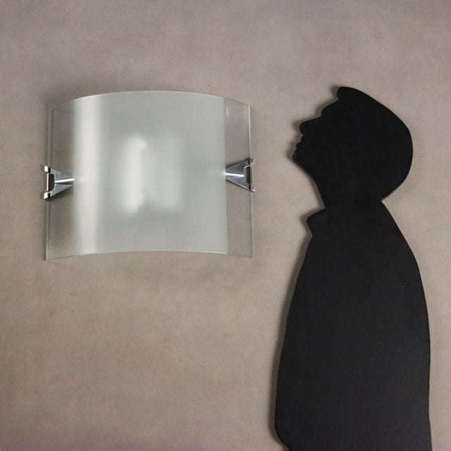 Pair of wall lamps with curved sandblasted glass diffuser in the central part and aluminium and steel hooks. This piece is...