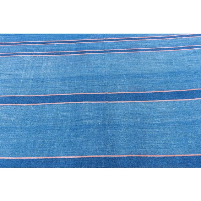This vintage 1955 Indian Dhurrie rug presents a striking yet refined interpretation of mid-century textile design, where...