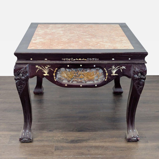 Carved wood table with a pink marble top. The legs have unique carved deity motifs, and the apron features carved center...