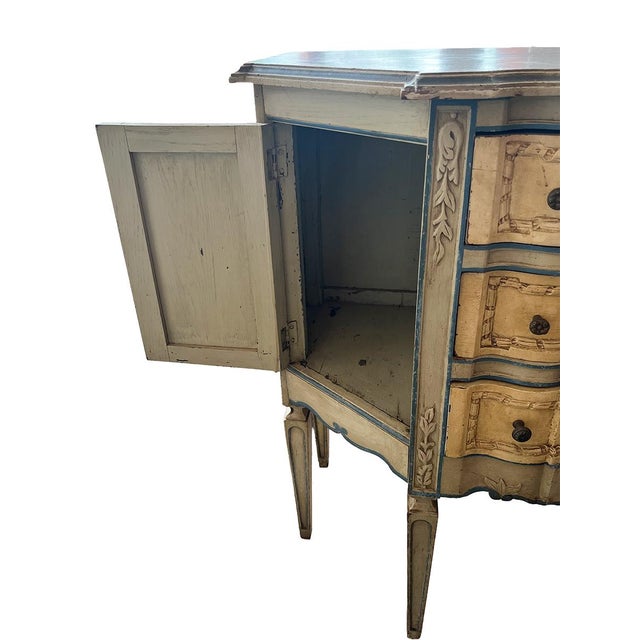 This demi-lune chest of drawers features three drawers, with small cabinets on either side. It stands on delicate, yet...