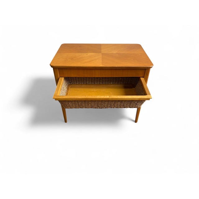 Elegant Swedish sewing table from the 1950s with veneered teak top, compartmentalized drawer, and woven cane basket. A...