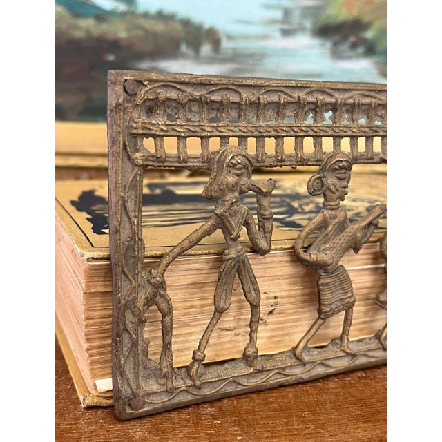 This Piece of primitive decorative wall art depicts a tribal dancing scene and is possibly brass in material. This Piece...