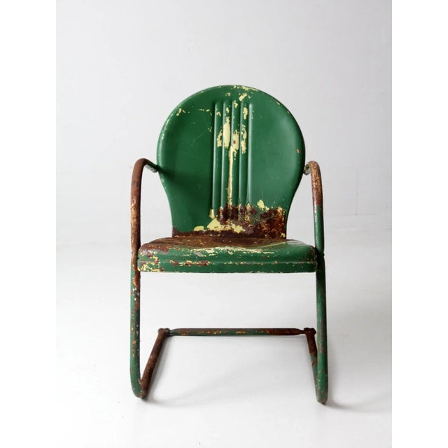 This is a mid-century patio chair. The art deco metal garden chair has a cantilever bouncer frame and scalloped back....