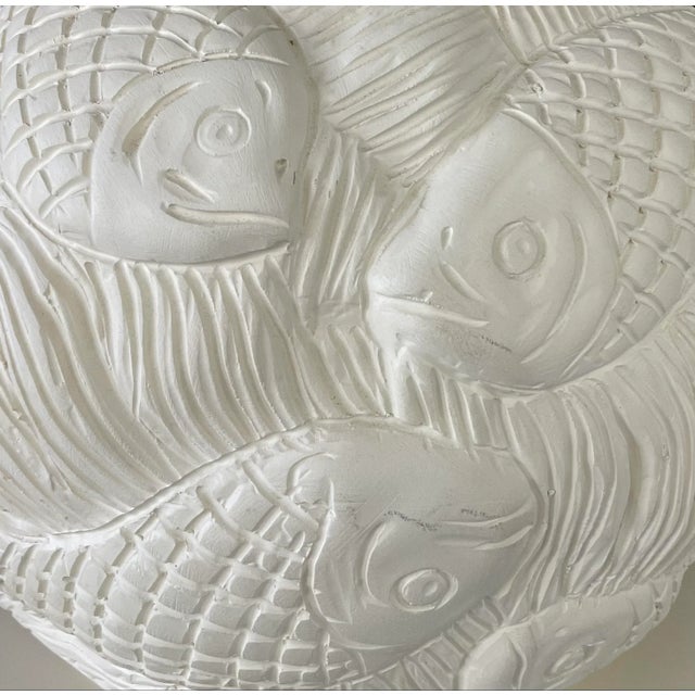 A beautiful hand crafted lamp with a pattern of swimming fish in a deeply incised method.