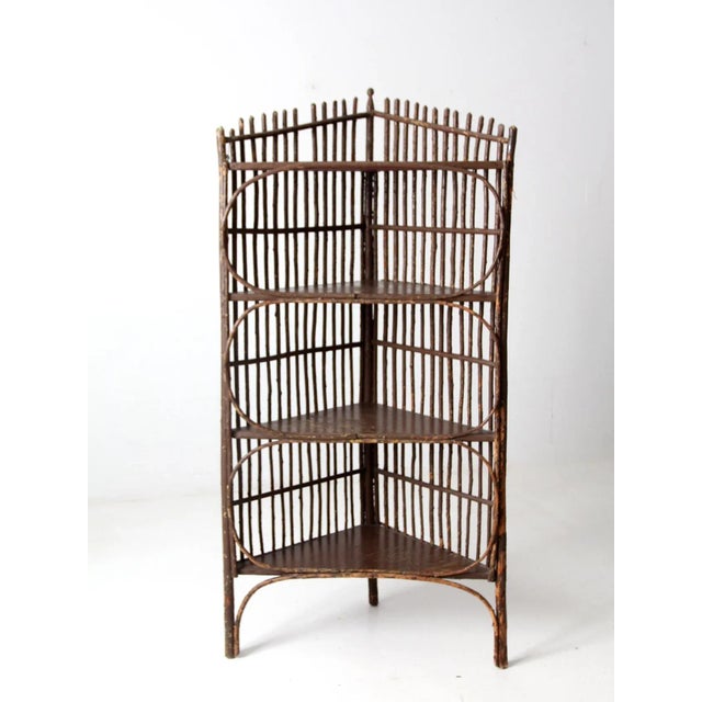 This antique wooden corner shelf features a twig-style design with a painted brown slat frame and four sturdy shelves....