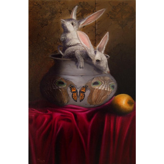 This oil on canvas artwork features two rabbits emerging from an intricately decorated bowl, creating a whimsical and...
