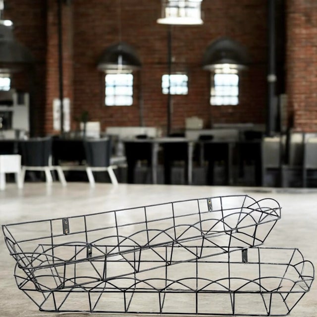 This pair of mid-20th century black wire baskets features a hand-welded geometric frame design and wall-mount brackets for...