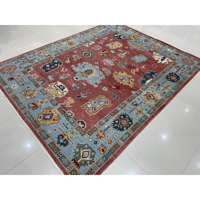 This hand knotted pile rug features a primary color palette of coral, salmon, and pink. Constructed entirely from wool,...