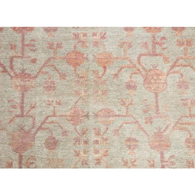 A beautiful early 20th century Central Asian Khotan rug with an all-over pomegranate pattern woven in muted crimson set...