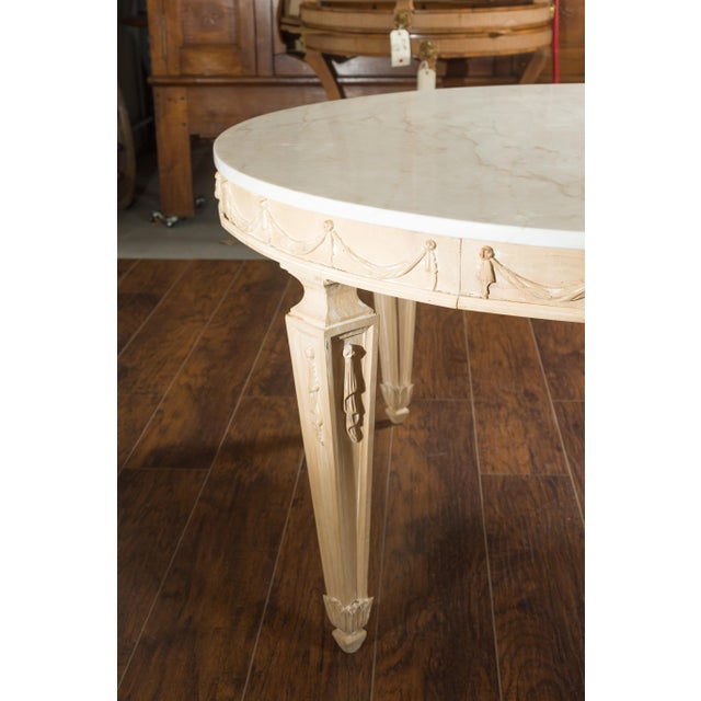 An Italian vintage neoclassical style pine dining room table from the mid-20th century, with white marble top, carved...