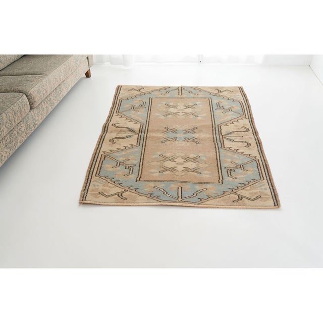 This is a vintage Turkish Oushak rug from the Mid 20th Century. The piece was hand-knotted.
