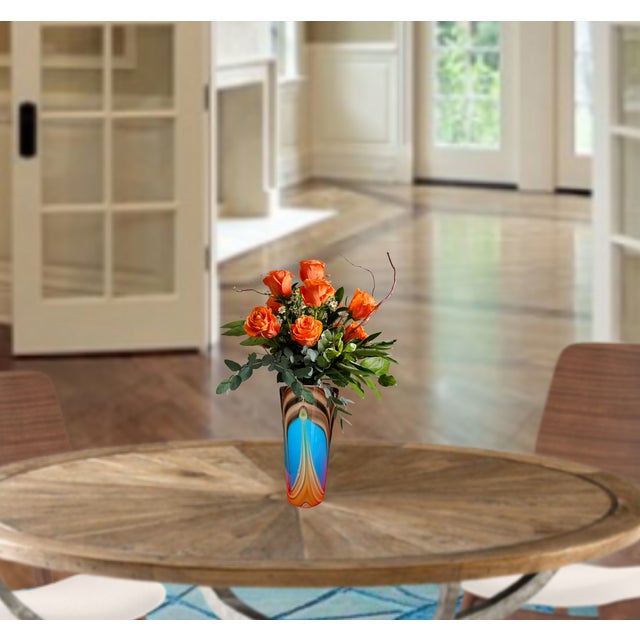 This hand-blown art glass vase stands at about 11 inches tall, with a narrow base that gently widens up toward a flared,...