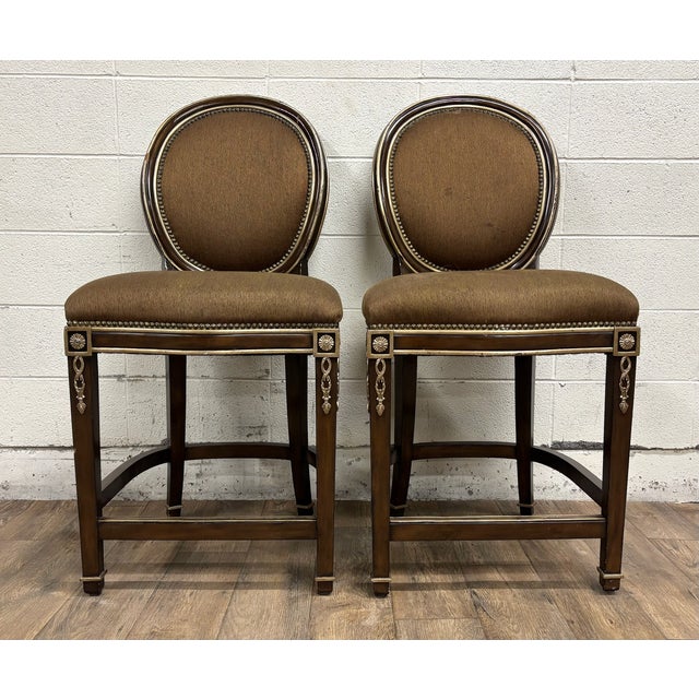 This is a gorgeous pair of Marge Carson French Louis XVI style round back bar stools in brown and gold with detailed...