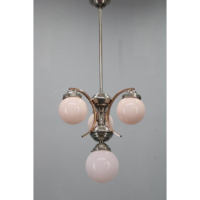 A refined art deco chandelier produced in czechoslovakia in the 1930s, showcasing a nickel-plated metal structure with...