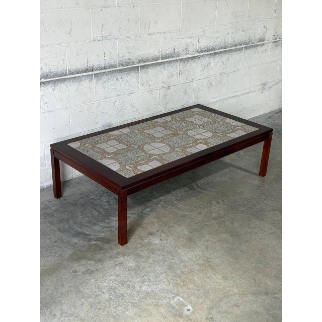 This rectangular coffee table features a minimalist profile elevated by straight legs. The expansive top is inset with...