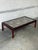 This rectangular coffee table features a minimalist profile elevated by straight legs. The expansive top is inset with...