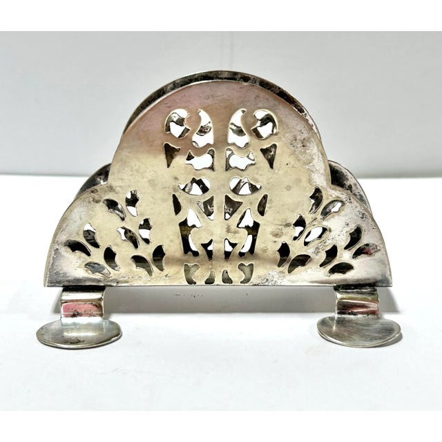 A 1950s English silverplate napkin holder by I.F.S. Ltd., featuring ornate pierced openwork and a gracefully arched...