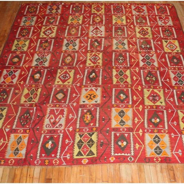 Vintage Turkish Kilim with a colorful repetitive square design on a cherry red colored ground. Measures: 8'10" x 10'11".
