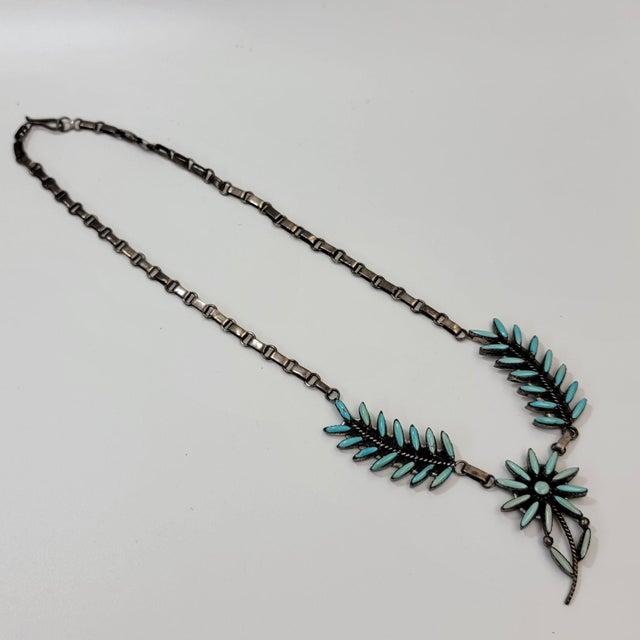 This necklace tells a story of craftsmanship, with its delicate needlepoint turquoise petals forming a radiant flower,...