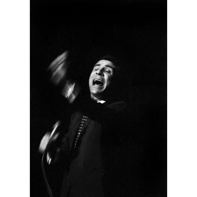 This photo shows the French singer Gilbert Bécaud during a concert in East Berlin in 1964. In the image, Bécaud is...