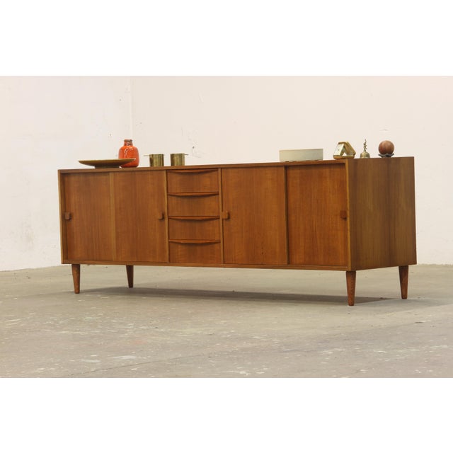 A sleek and stylish vintage teak sideboard from Denmark, crafted in the 1960s. This elegant piece features four doors—two...