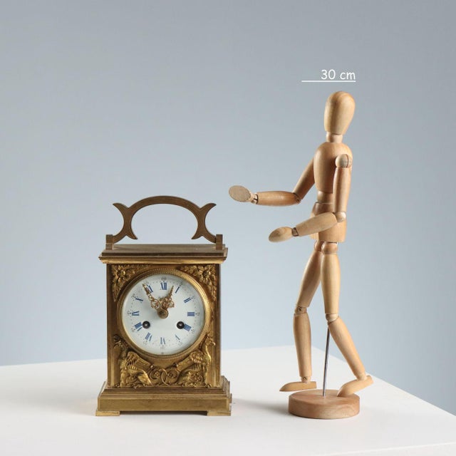 5-Jewel table clock with finely engraved and chiseled bronze mechanical movement. The front features a decoration of...