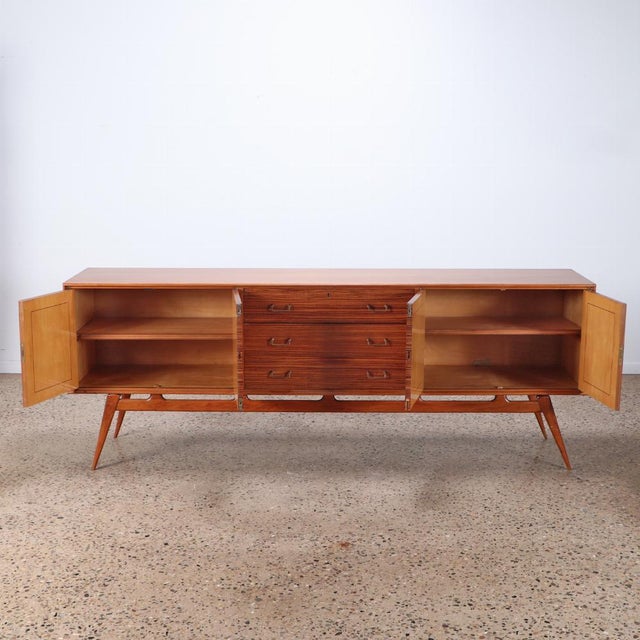 The piece features four doors opening to reveal lots of shelf space and all flanking three drawers, the top fitted with...