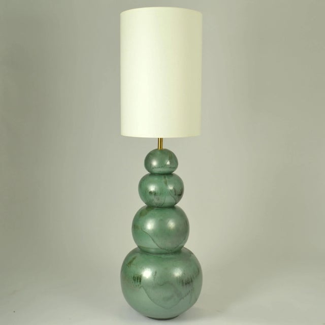 Pair of ceramic floor lights made of four globes that are descending in size and are stacked on top of each other to form...