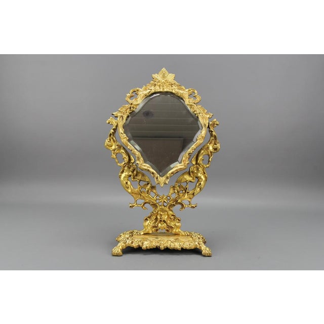 French Louis XIV Style bronze and brass faceted desktop mirror from the 1920s Adorned with typical Louis XIV-style...