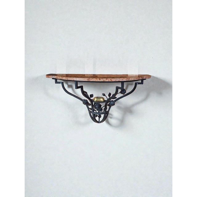 Wall-mounted console table crafted from wrought metal with floral decorations and a red Verona marble top. The console...