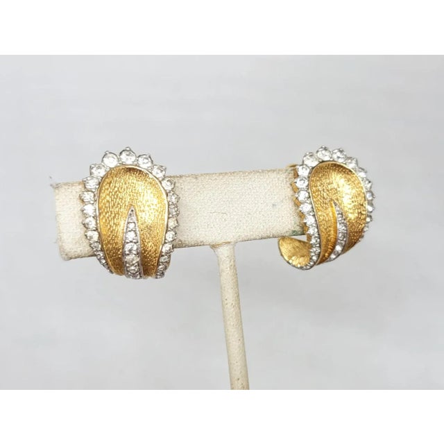 This is part of Chairish’s Costume Jewelry assortment. 1960s textured goldtone with rounded top and curled bottom with...