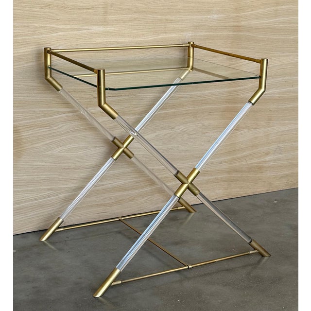 This sculptural serving table features a X Form legs. This top is aligned with a geometrical double lucite frame that...