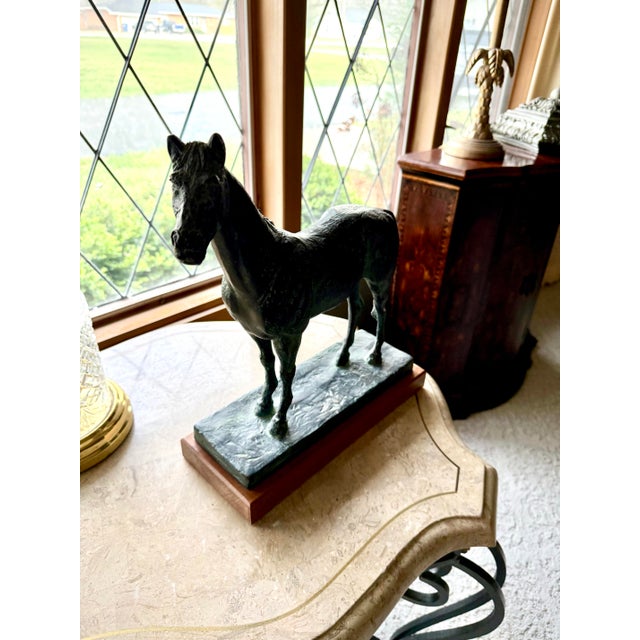 Striking bronze horse sculpture featuring beautiful natural green patina, mounted on substantial black marble base with...