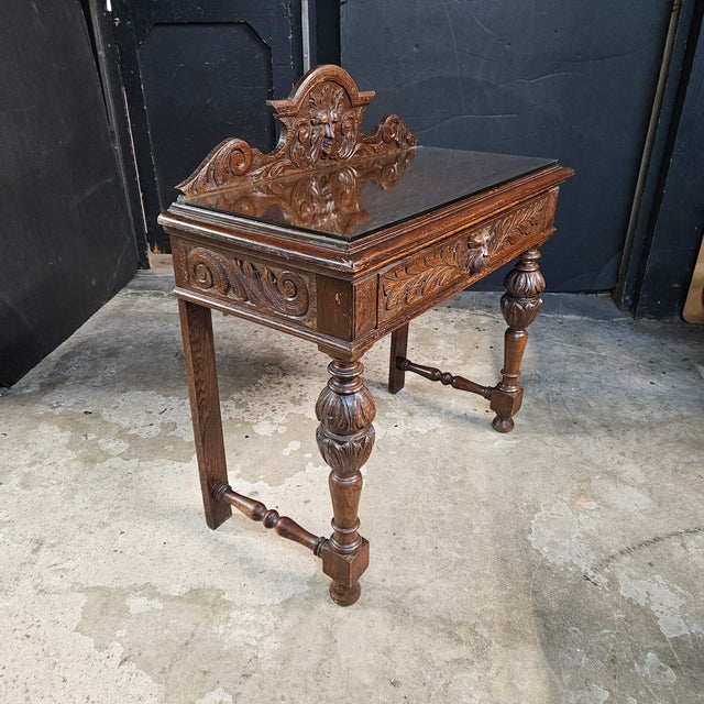 This English Oak Heavily Carved Console Table With Drawer has bulbous front legs and griffin carvings on the backsplash...