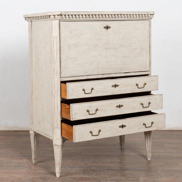 Elegant yet compact white Gustavian style secretary also known as a bureau, with dentil molding, fluted sides and tapered...