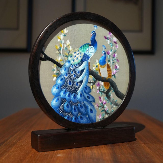 This exquisite Suzhou (Su) embroidery piece features a majestic peacock perched gracefully on a blossoming branch,...