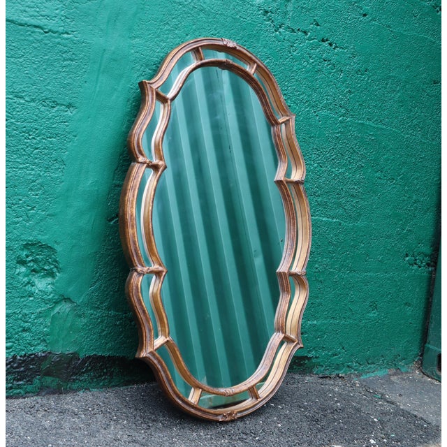 This large vintage Regency style mirror has a unique scalloped oval frame of painted gold wood. Carved ornate...